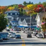 A street in a small town in New Hampshire with cars parked in the street.