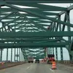A green bridge in New Hampshire with a car driving over it.