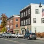 A street in a small town in New Hampshire with cars parked in the street.