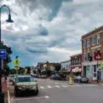 A street in New Hampshire with cars parked on it under a cloudy sky.